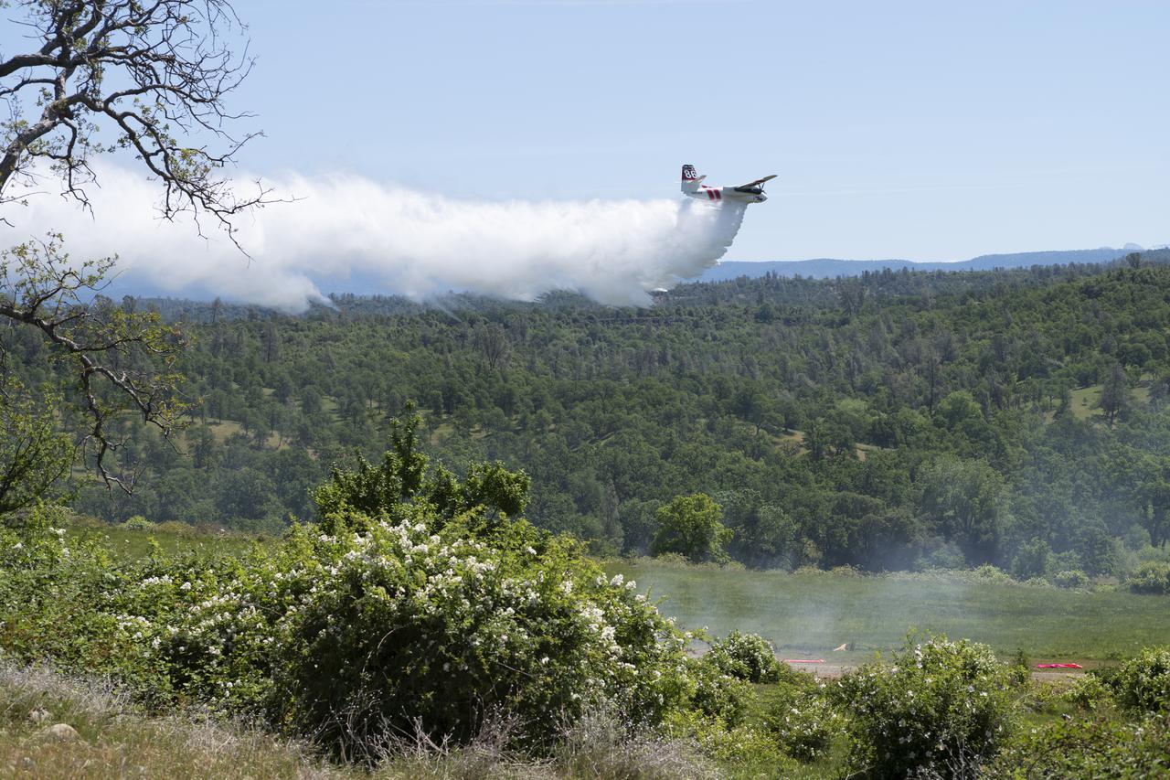 A Cal Fire S2-T airtanker is seen as it drops water on a simulated wildfire, Tuesday, May 4, 2021 as Cal Fire conducts aerial fire fighting training exercises near Redding, California. STEReO, the Scalable Traffic Management for Emergency Response Operations project, led by NASA’s Ames Research Center, builds on NASA’s expertise in air traffic management, human factors research, and autonomous technology development to apply the agency’s work in Unmanned Aircraft Systems Traffic Management, or UTM, to public safety uses. Photo Credit: (NASA/Joel Kowsky)