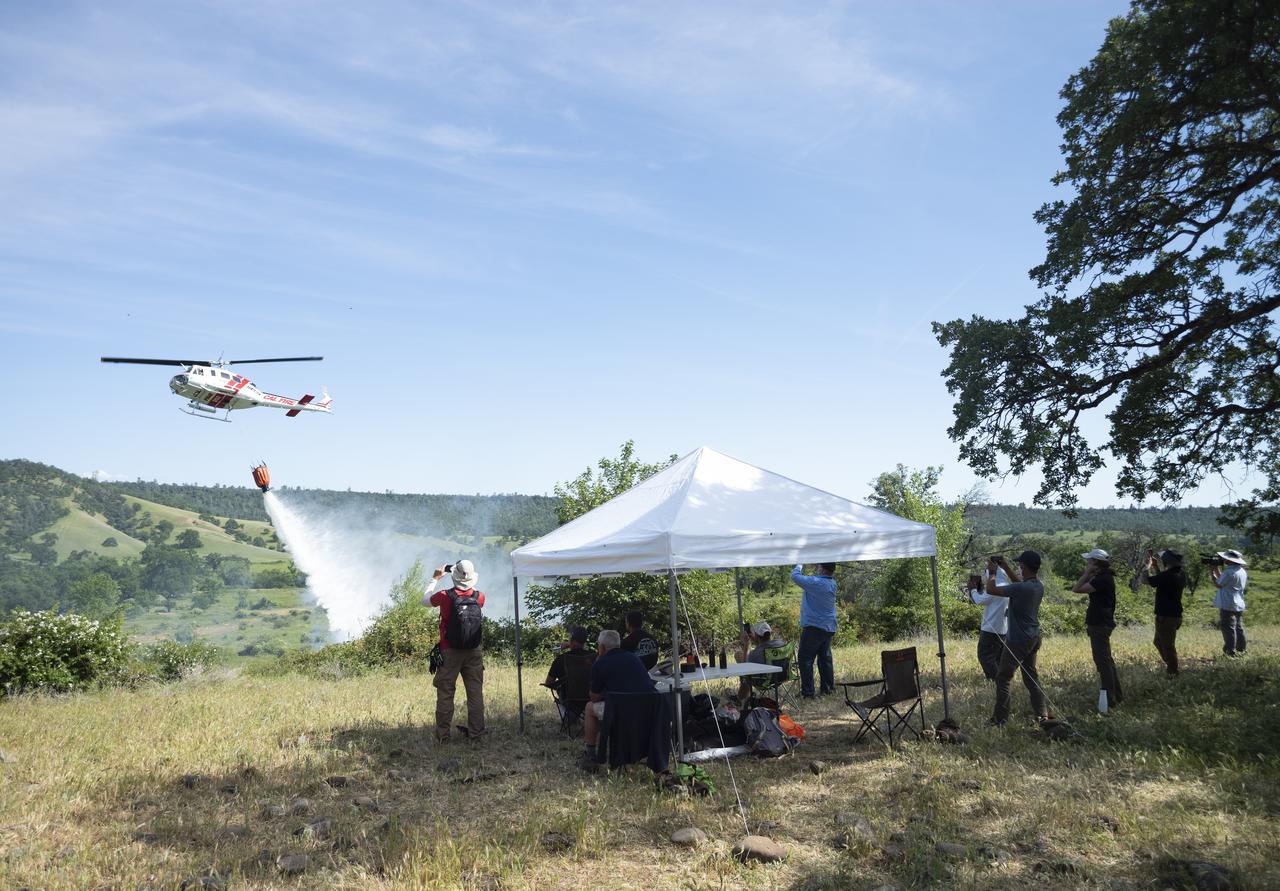 STEReO, the Scalable Traffic Management for Emergency Response Operations project, team members watch as a Cal Fire UH-1H Super Huey helicopter drops water on a simulated wildfire, Tuesday, May 4, 2021 as Cal Fire conducts aerial fire fighting training exercises near Redding, California.  STEReO, the Scalable Traffic Management for Emergency Response Operations project, led by NASA’s Ames Research Center, builds on NASA’s expertise in air traffic management, human factors research, and autonomous technology development to apply the agency’s work in Unmanned Aircraft Systems Traffic Management, or UTM, to public safety uses. Photo Credit: (NASA/Joel Kowsky)