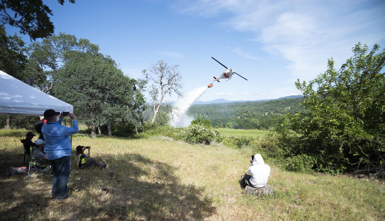 STEReO, the Scalable Traffic Management for Emergency Response Operations project, team members watch as a Cal Fire UH-1H Super Huey helicopter drops water on a simulated wildfire, Tuesday, May 4, 2021 as Cal Fire conducts aerial fire fighting training exercises near Redding, California.  STEReO, the Scalable Traffic Management for Emergency Response Operations project, led by NASA’s Ames Research Center, builds on NASA’s expertise in air traffic management, human factors research, and autonomous technology development to apply the agency’s work in Unmanned Aircraft Systems Traffic Management, or UTM, to public safety uses. Photo Credit: (NASA/Joel Kowsky)