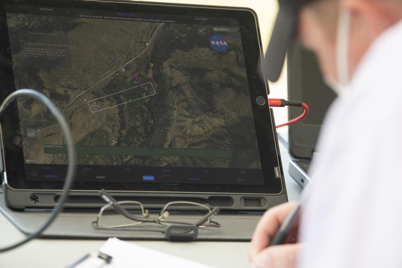 A tablet displaying a version of the Unmanned Aircraft Systems Traffic Management System (UTM) is seen during STEReO, the Scalable Traffic Management for Emergency Response Operations project, field testing, Wednesday, May 5, 2021 as Cal Fire conducts aerial fire fighting training exercises near Redding, California.  STEReO, the Scalable Traffic Management for Emergency Response Operations project, led by NASA’s Ames Research Center, builds on NASA’s expertise in air traffic management, human factors research, and autonomous technology development to apply the agency’s work in Unmanned Aircraft Systems Traffic Management, or UTM, to public safety uses. Photo Credit: (NASA/Joel Kowsky)