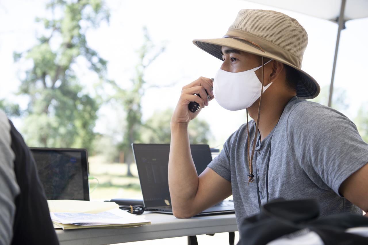 Josh Baculi, autonomy researcher for STEReO, the Scalable Traffic Management for Emergency Response Operations project, at NASA's Ames Research Center, makes a radio call during simulated drone operations as part of STEReO field testing, Wednesday, May 5, 2021 as Cal Fire conducts aerial fire fighting training exercises near Redding, California.  STEReO, the Scalable Traffic Management for Emergency Response Operations project, led by NASA’s Ames Research Center, builds on NASA’s expertise in air traffic management, human factors research, and autonomous technology development to apply the agency’s work in Unmanned Aircraft Systems Traffic Management, or UTM, to public safety uses. Photo Credit: (NASA/Joel Kowsky)