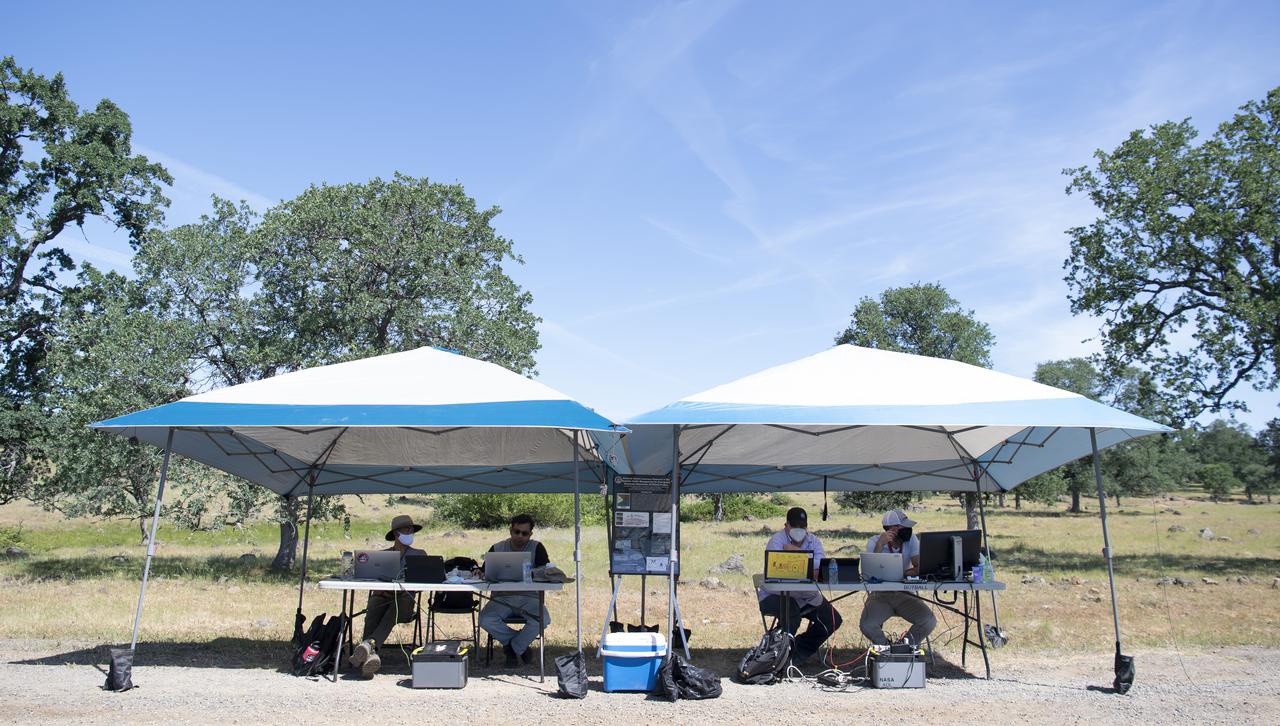 Josh Baculi left, and Anjan Chakrabarty, second from left, autonomy researchers for STEReO, the Scalable Traffic Management for Emergency Response Operations project, from NASA's Ames Research Center, are seen with Robert McSwain, co-principle investigator and autonomy researcher for STEReO, second from right, and Bryan Petty, autonomy researcher for STEReO, right, from NASA's Langley Research Center, during STEReO field testing, Wednesday, May 5, 2021 as Cal Fire conducts aerial fire fighting training exercises near Redding, California. STEReO, the Scalable Traffic Management for Emergency Response Operations project, led by NASA’s Ames Research Center, builds on NASA’s expertise in air traffic management, human factors research, and autonomous technology development to apply the agency’s work in Unmanned Aircraft Systems Traffic Management, or UTM, to public safety uses. Photo Credit: (NASA/Joel Kowsky)