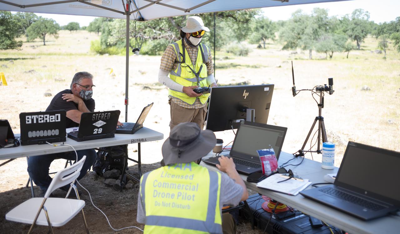 Bill McCarthy, software engineer and research laptop operator for STEReO, the Scalable Traffic Management for Emergency Response Operations project, at NASA's Ames Research Center, left, Jonas Jonsson, pilot in command for STEReO, at NASA's Ames Research Center, standing center, and Zach Roberts, pilot computer operator for STEReO, at NASA's Ames Research Center, seated center, are seen during STEReO field testing, Wednesday, May 5, 2021 as Cal Fire conducts aerial fire fighting training exercises near Redding, California. STEReO, the Scalable Traffic Management for Emergency Response Operations project, led by NASA’s Ames Research Center, builds on NASA’s expertise in air traffic management, human factors research, and autonomous technology development to apply the agency’s work in Unmanned Aircraft Systems Traffic Management, or UTM, to public safety uses. Photo Credit: (NASA/Joel Kowsky)