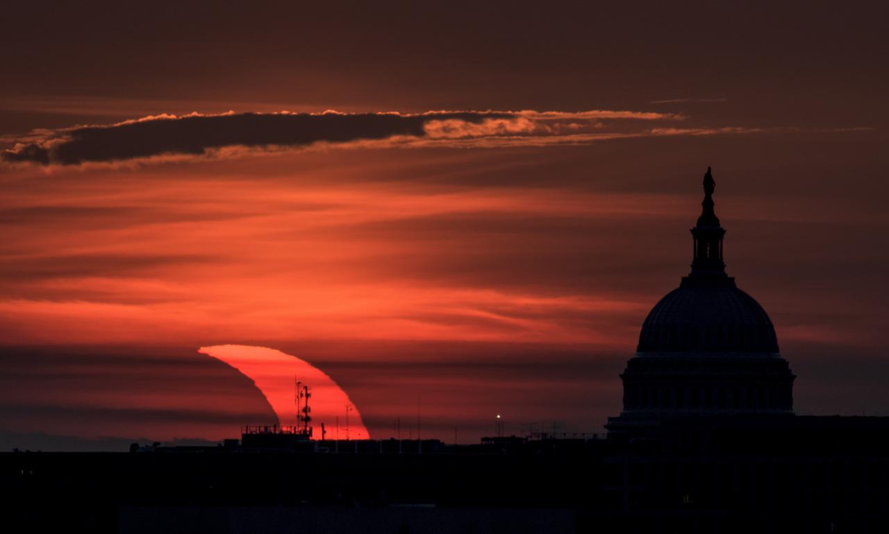 A partial solar eclipse is seen as the sun rises to the left of the United States Capitol building, Thursday, June 10, 2021, as seen from Arlington, Virginia. The annular or “ring of fire” solar eclipse is only visible to some people in Greenland, Northern Russia, and Canada. Photo Credit: (NASA/Bill Ingalls)