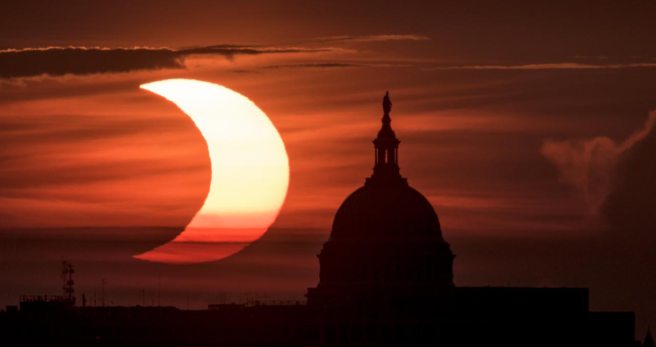 A partial solar eclipse is seen as the sun rises to the left of the United States Capitol building, Thursday, June 10, 2021, as seen from Arlington, Virginia. The annular or “ring of fire” solar eclipse is only visible to some people in Greenland, Northern Russia, and Canada. Photo Credit: (NASA/Bill Ingalls)