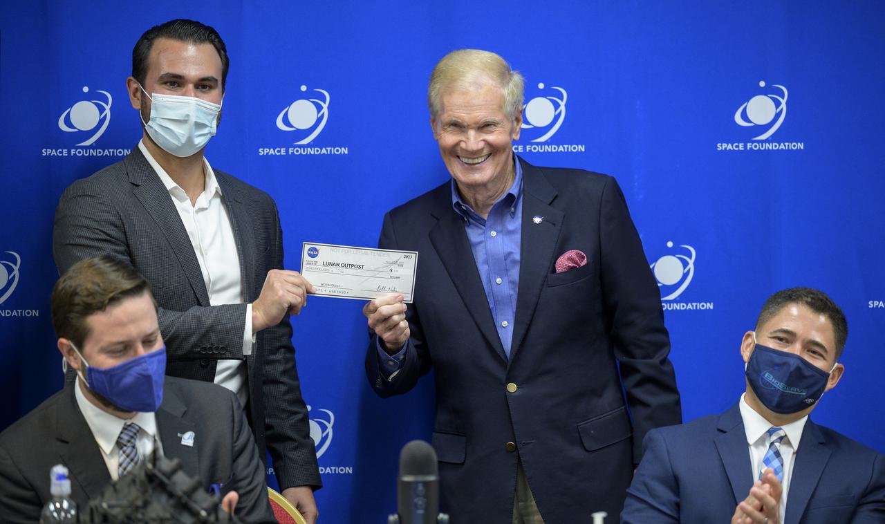 NASA Administrator Bill Nelson presents Justin Cyrus, CEO, Lunar Outpost of Golden, Colorado a check for $0.10 during an event to introduce media to three local Colorado companies and university partners that help make NASA’s missions possible, Monday, Aug. 23, 2021, during the 36th Space Symposium in Colorado Springs, Colorado. Lunar Outpost is one of four companies that will collect space resources and transfer ownership to NASA; Lunar Outpost proposed collection for $1 following arrival of a lander to the lunar South Pole in 2023 and is on track to accomplish this a year early as part of the Intuitive Machines 2 Mission in 2022. They recently passed their first milestone and is the first of the four proposals selected to do so, and will receive a payment of $0.10.  Photo Credit: (NASA/Bill Ingalls)