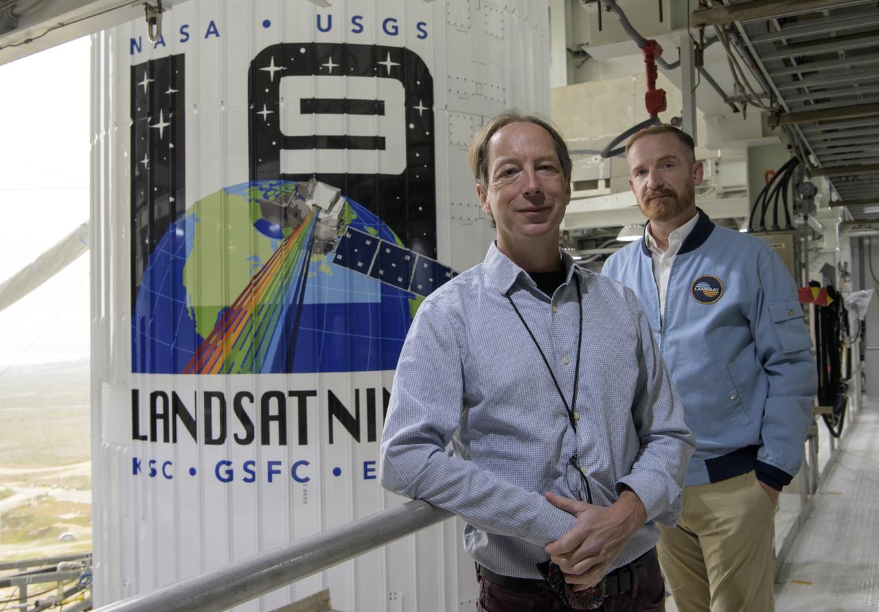 NASA Landsat 9 Project Scientist Jeff Masek, left, and Actor Marc Evan Jackson, pose for a photograph by the United Launch Alliance (ULA) Atlas V rocket with the Landsat 9 satellite onboard, Sunday, Sept. 26, 2021, at Vandenberg Space Force Base in California. The Landsat 9 satellite, a joint NASA/U.S. Geological Survey mission that will continue the legacy of monitoring Earth’s land and coastal regions, is scheduled for liftoff Monday, Sept. 27. Photo Credit: (NASA/Bill Ingalls)