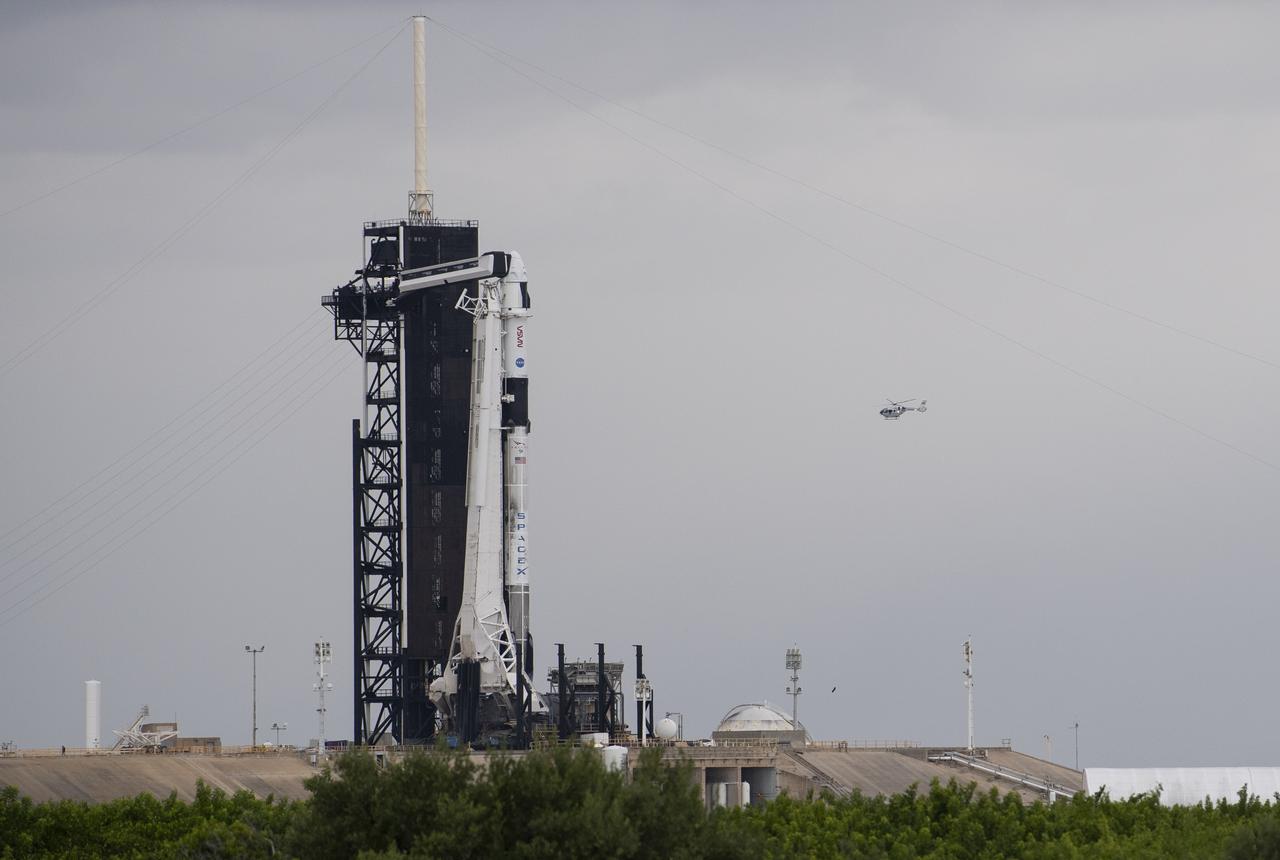 A NASA helicopter is seen flying past a SpaceX Falcon 9 rocket with the company's Crew Dragon spacecraft onboard on the launch pad at Launch Complex 39A as preparations continue for the Crew-3 mission, Friday, Oct. 29, 2021, at NASA’s Kennedy Space Center in Florida. NASA’s SpaceX Crew-3 mission is the third crew rotation mission of the SpaceX Crew Dragon spacecraft and Falcon 9 rocket to the International Space Station as part of the agency’s Commercial Crew Program. NASA astronauts Raja Chari, Tom Marshburn, Kayla Barron, and ESA (European Space Agency) astronaut Matthias Maurer are scheduled to launch on Nov. 3 at 1:10 a.m. ET, from Launch Complex 39A at the Kennedy Space Center. Photo Credit: (NASA/Joel Kowsky)