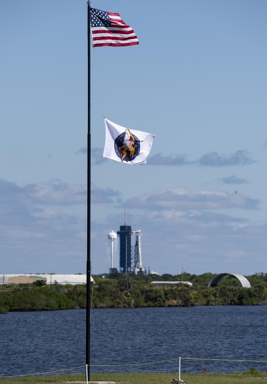 The American flag and a flag bearing the patch for NASA’s SpaceX Crew-3 mission are seen at the Press Site at NASA’s Kennedy Space Center, Sunday, Oct. 31, 2021, in Florida. NASA’s SpaceX Crew-3 mission is the third crew rotation mission of the SpaceX Crew Dragon spacecraft and Falcon 9 rocket to the International Space Station as part of the agency’s Commercial Crew Program. NASA astronauts Raja Chari, Tom Marshburn, Kayla Barron, and ESA (European Space Agency) astronaut Matthias Maurer are scheduled to launch on Nov. 3 at 1:10 a.m. ET, from Launch Complex 39A at the Kennedy Space Center. Photo Credit: (NASA/Joel Kowsky)