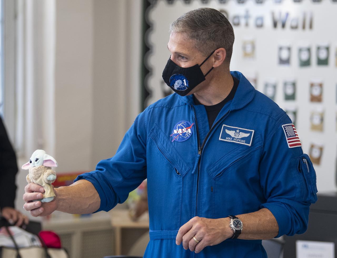 NASA astronaut Mike Hopkins shows his crew’s “zero-G indicator” as he speaks with students about his time aboard the International Space Station during the Crew-1 mission, Thursday, Nov. 18, 2021, at Garfield Elementary School in Washington, DC. Hopkins and fellow NASA astronauts Shannon Walker, Victor Glover, and Japan Aerospace Exploration Agency (JAXA) astronaut Soichi Noguchi launched on the first crew rotation mission to the International Space Station for SpaceX’s Falcon 9 and Crew Dragon spacecraft as part of the agency’s Commercial Crew Program and spent 168 days in space across Expeditions 64 and 65. Photo Credit: (NASA/Joel Kowsky)