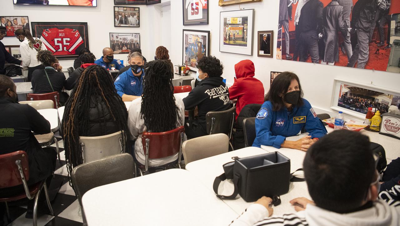 NASA astronauts Victor Glover, back left, Mike Hopkins, middle, and Shannon Walker, front right, speak with students about his time aboard the International Space Station, Thursday, Nov. 18, 2021, at Ben’s Chili Bowl in Washington, DC. Students from Cardozo Educational Campus, Friendship Technology Preparatory High School, McKinley Technical High School, Phelps High School, and Wilson High School heard NASA astronauts Glover, Hopkins, and Walker speak about the Crew-1 mission, the first crew rotation mission to the International Space Station for SpaceX’s Falcon 9 and Crew Dragon spacecraft as part of the agency’s Commercial Crew Program and the 168 days they spent in space across Expeditions 64 and 65. Photo Credit: (NASA/Joel Kowsky)