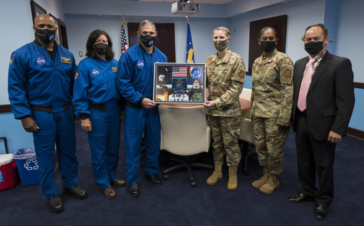 SpaceX Crew-1 NASA astronauts, from left, Victor Glover, Shannon Walker, and Mike Hopkins, pose for a photo after presenting a montage from their mission to Col. Catherine Logan, commander of Joint Base Anacostia-Bolling (JBAB), Chief Master Sergeant at Joint Base Anacostia-Bolling, Christy L. Peterson, and Director of Staff at Joint Base Anacostia-Bolling, John Eichstadt, Friday, Nov. 19, 2021, in Washington. Hopkins, Glover, Walker, and Japan Aerospace Exploration Agency (JAXA) astronaut Soichi Noguchi, launched on the first crew rotation mission to the International Space Station for SpaceX’s Falcon 9 and Crew Dragon spacecraft as part of the agency’s Commercial Crew Program and spent 168 days in space across Expeditions 64 and 65. Photo Credit: (NASA/Aubrey Gemignani)