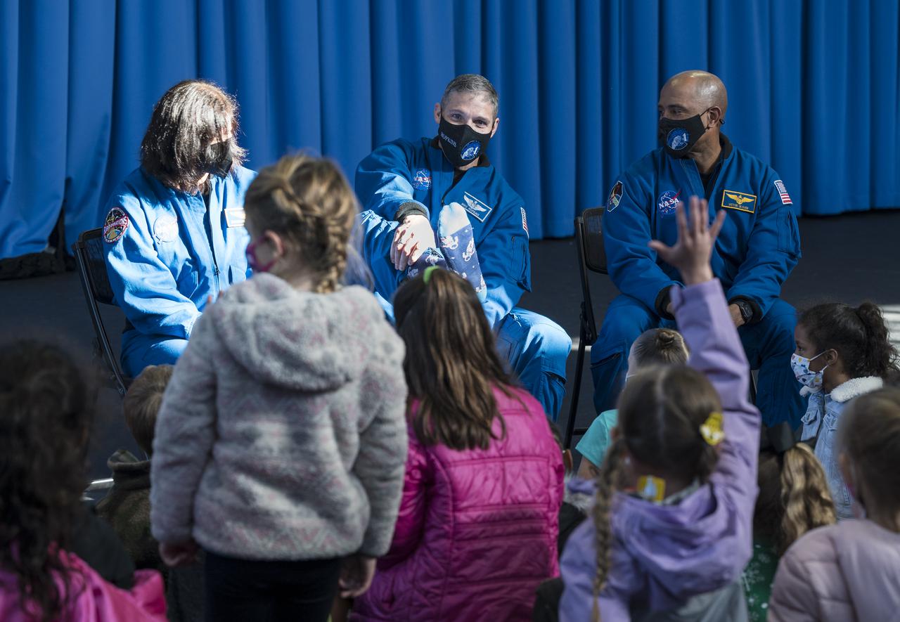 SpaceX Crew-1 NASA astronaut Mike Hopkins, center, displays one of the gifts that he received while living at the International Space Station, while he and crew mates NASA astronaut Shannon Walker, left, and Victor Glover, right, answer questions by students from the Learn DC public charter school at Joint Base Anacostia-Bolling (JBAB), Friday, Nov. 19, 2021, in Washington. Hopkins, Glover, Walker, and Japan Aerospace Exploration Agency (JAXA) astronaut Soichi Noguchi, launched on the first crew rotation mission to the International Space Station for SpaceX’s Falcon 9 and Crew Dragon spacecraft as part of the agency’s Commercial Crew Program and spent 168 days in space across Expeditions 64 and 65. Photo Credit: (NASA/Aubrey Gemignani)