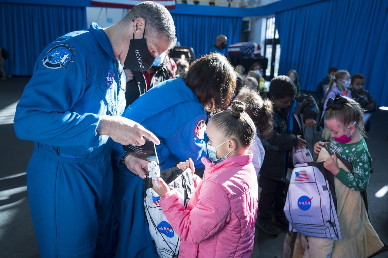 SpaceX Crew-1 NASA astronaut Mike Hopkins and Shannon Walker, hand out NASA bags to students of the Learn DC public charter school at Joint Base Anacostia-Bolling (JBAB), Friday, Nov. 19, 2021, in Washington. Hopkins, Walker, NASA astronaut Victor Glover, and Japan Aerospace Exploration Agency (JAXA) astronaut Soichi Noguchi, launched on the first crew rotation mission to the International Space Station for SpaceX’s Falcon 9 and Crew Dragon spacecraft as part of the agency’s Commercial Crew Program and spent 168 days in space across Expeditions 64 and 65. Photo Credit: (NASA/Aubrey Gemignani)