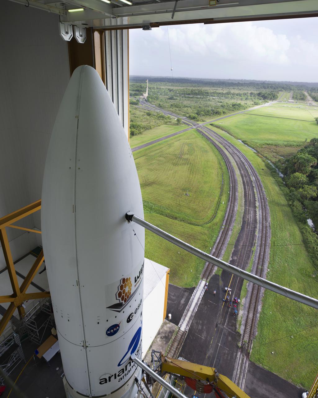 Arianespace's Ariane 5 rocket with NASA’s James Webb Space Telescope onboard, is seen in the final assembly building ahead of the planned roll to the launch pad, Thursday, Dec. 23, 2021, at Europe’s Spaceport, the Guiana Space Center in Kourou, French Guiana. The James Webb Space Telescope (sometimes called JWST or Webb) is a large infrared telescope with a 21.3 foot (6.5 meter) primary mirror. The observatory will study every phase of cosmic history—from within our solar system to the most distant observable galaxies in the early universe. Photo Credit: (NASA/Chris Gunn)