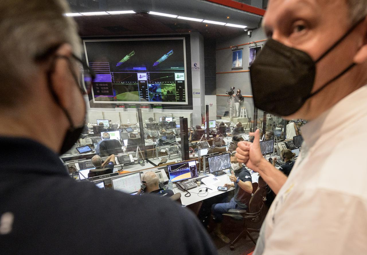 Arianespace CEO Stéphane Israël, at desk, and NASA Associate Administrator for the Science Mission Directorate Thomas Zurbuchen, right, both gives a thumbs up after receiving confirmation that the Ariane 5 rocket upper stage shut down as planed a few minutes before separation from the James Webb Space Telescope, Saturday, Dec. 25, 2021, in the Jupiter Hall of the Guiana Space Centre in Kourou, French Guiana. The James Webb Space Telescope (sometimes called JWST or Webb) is a large infrared telescope with a 21.3 foot (6.5 meter) primary mirror. The observatory will study every phase of cosmic history—from within our solar system to the most distant observable galaxies in the early universe. Photo Credit: (NASA/Bill Ingalls)