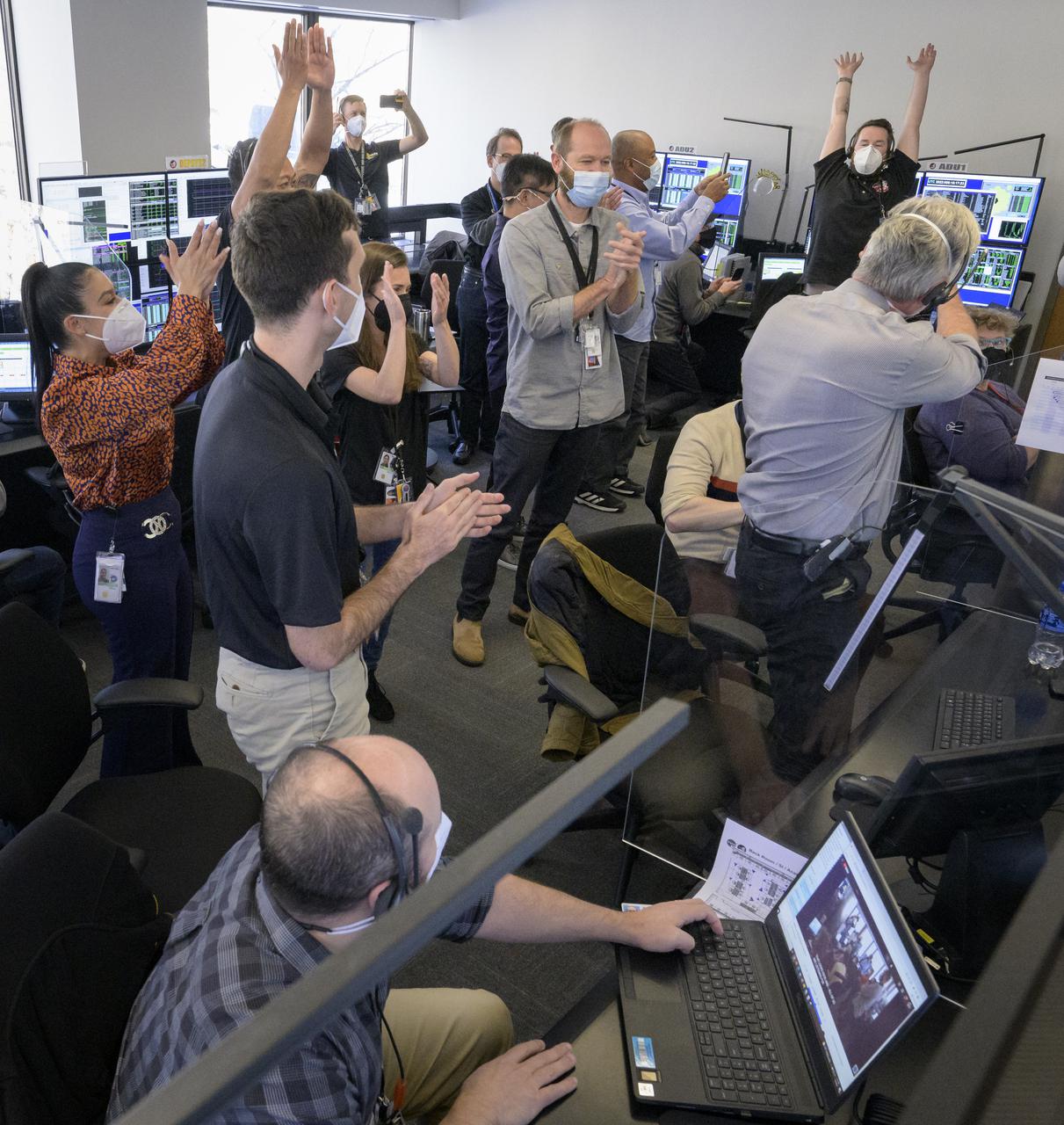 NASA’s James Webb Space Telescope mission operations team celebrates, Saturday, Jan. 8, 2022, at the Space Telescope Science Institute in Baltimore, after confirming that the observatory’s final primary mirror wing successfully extended and locked into place. With Webb’s 21.3-foot (6.5-meter) primary mirror fully deployed, the infrared observatory has completed its unprecedented process of unfolding in space to prepare for science operations. The observatory will study every phase of cosmic history—from within our solar system to the most distant observable galaxies in the early universe. Photo Credit: (NASA/Bill Ingalls)