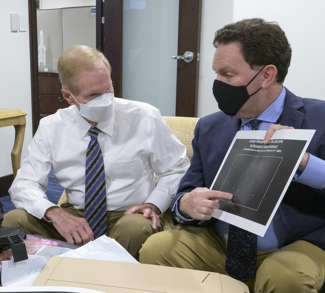 NASA Administrator Bill Nelson, left, is shown an early mirror alignment image from the James Webb Space Telescope, by NASA Webb Optical Telescope Element Manager Lee Feinberg, Monday, Feb., 7, 2022, at the Mary W. Jackson NASA Headquarters building in Washington. This engineering visual, which features 18 unfocused dots of light, demonstrates that the Webb team has successfully identified starlight through each of Webb’s 18 hexagonal mirror segments – the starting point in a months-long process to progressively align the segments into a single, precise mirror to prepare the telescope for science. Photo Credit: (NASA/Bill Ingalls)