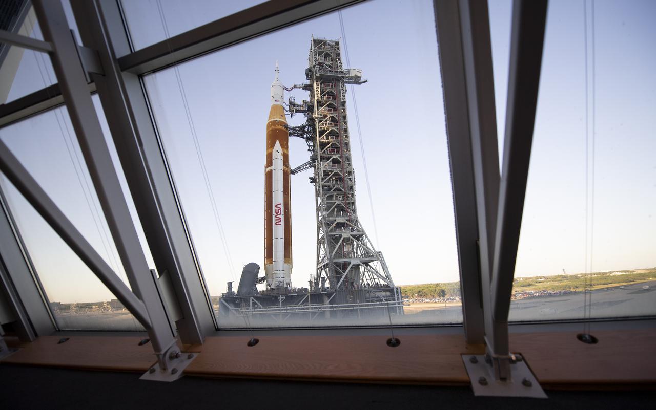 NASA’s Space Launch System (SLS) rocket with the Orion spacecraft aboard is seen through the windows of Firing Room One in the Rocco A. Petrone Launch Control Center atop a mobile launcher as it rolls out of High Bay 3 of the Vehicle Assembly Building for the first time to Launch Complex 39B, Thursday, March 17, 2022, at NASA’s Kennedy Space Center in Florida. Ahead of NASA’s Artemis I flight test, the fully stacked and integrated SLS rocket and Orion spacecraft will undergo a wet dress rehearsal at Launch Complex 39B to verify systems and practice countdown procedures for the first launch. Photo Credit: (NASA/Joel Kowsky)