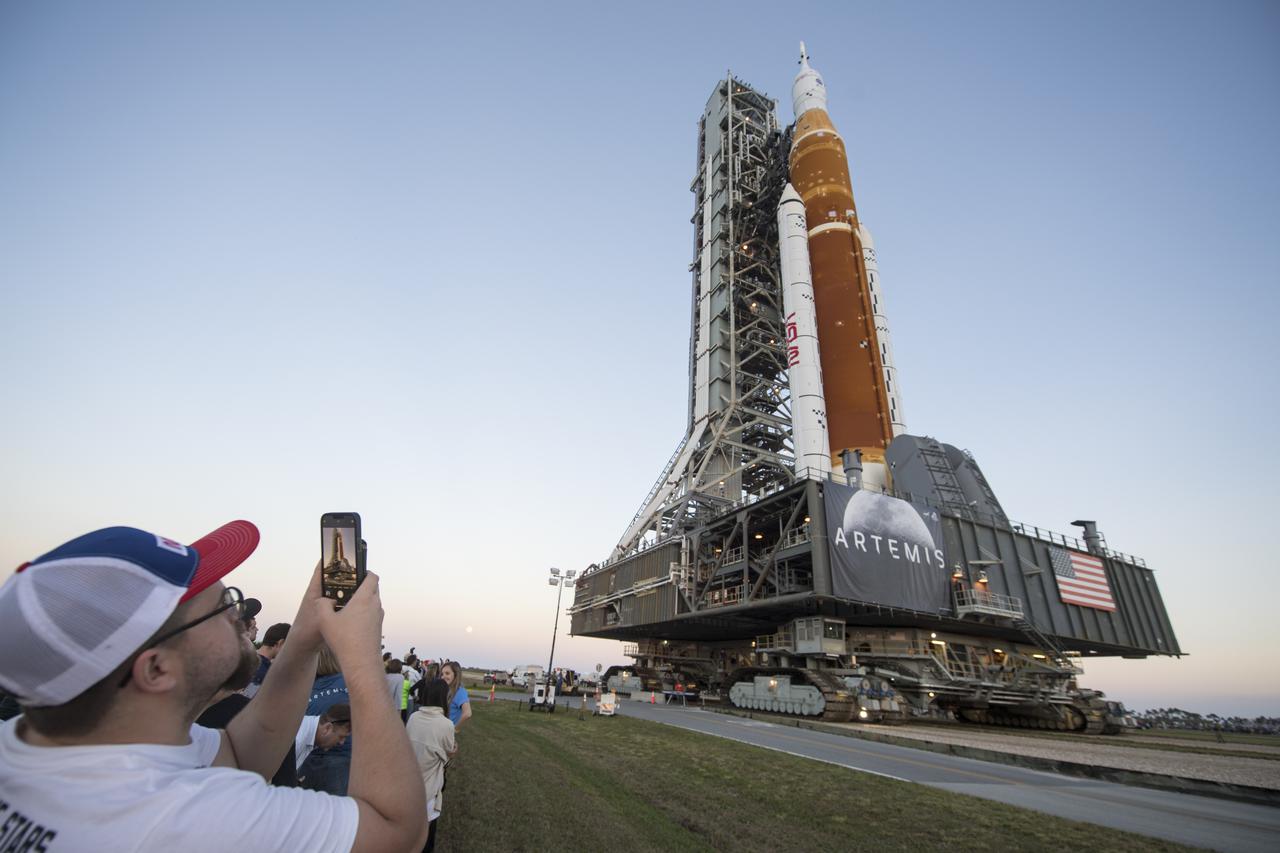Invited guests and NASA employees take photos as NASA’s Space Launch System (SLS) rocket with the Orion spacecraft aboard is rolled out of High Bay 3 of the Vehicle Assembly Building for the first time, Thursday, March 17, 2022, at NASA’s Kennedy Space Center in Florida. Ahead of NASA’s Artemis I flight test, the fully stacked and integrated SLS rocket and Orion spacecraft will undergo a wet dress rehearsal at Launch Complex 39B to verify systems and practice countdown procedures for the first launch. Photo Credit: (NASA/Aubrey Gemignani)