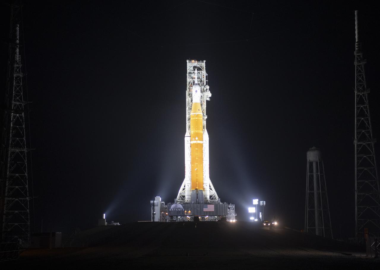 NASA’s Space Launch System (SLS) rocket with the Orion spacecraft aboard is seen illuminated by spotlights atop a mobile launcher at Launch Complex 39B, Friday, March 18, 2022, after being rollout out to the launch pad for the first time at NASA’s Kennedy Space Center in Florida. Ahead of NASA’s Artemis I flight test, the fully stacked and integrated SLS rocket and Orion spacecraft will undergo a wet dress rehearsal at Launch Complex 39B to verify systems and practice countdown procedures for the first launch. Photo Credit: (NASA/Joel Kowsky)