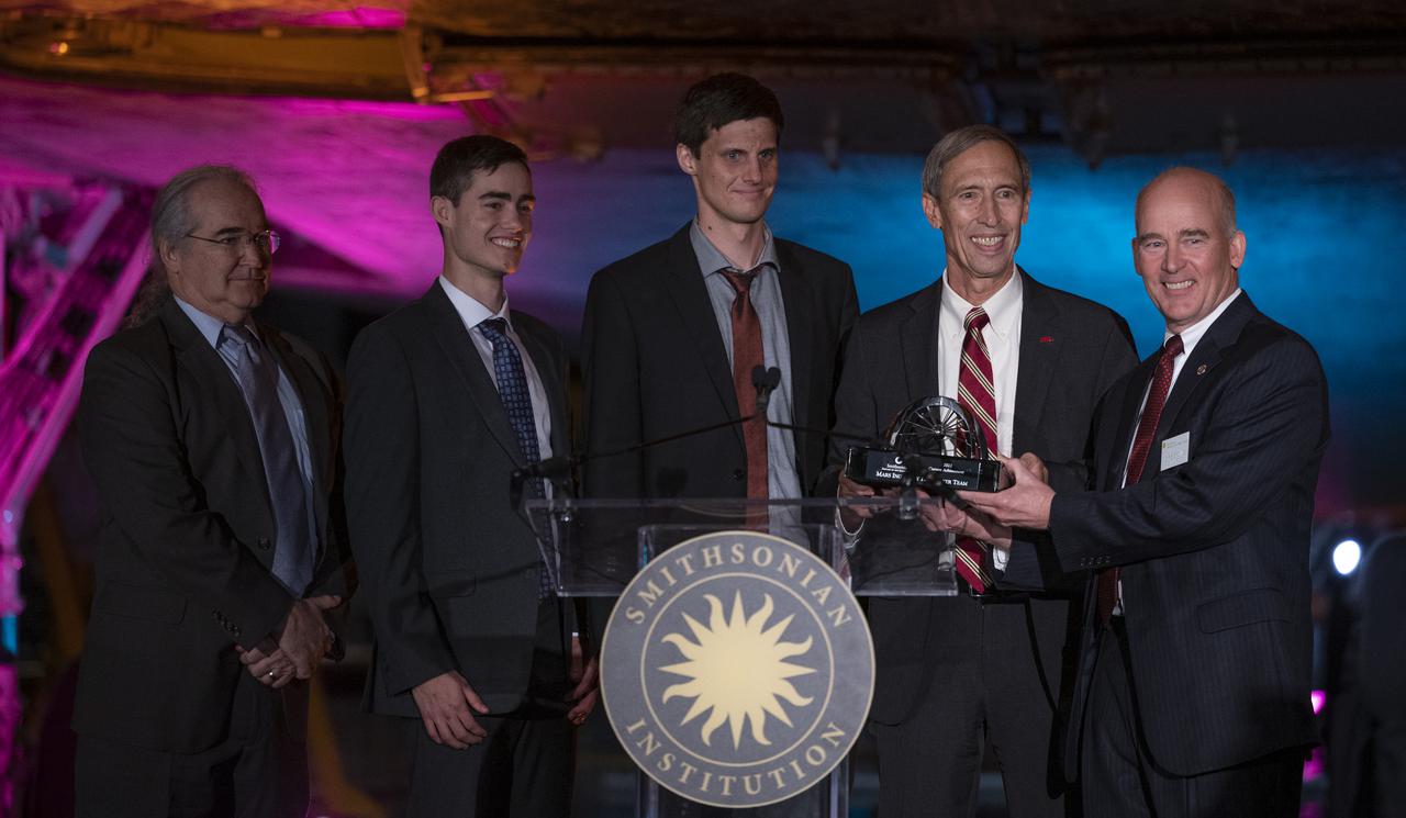 Interim director of NASA’s Jet Propulsion Laboratory Lt. Gen. Larry James, USAF (Ret.), second from right, accepts the 2022 Michael Collins Trophy for Current Achievement from Christopher Browne, acting director of the Smithsonian’s National Air and Space Museum, right, on behalf of MiMi Aung and the Mars Ingenuity Helicopter Team, Thursday, March 24, 2022, at the Smithsonian National Air and Space Museum’s Steven F. Udvar-Hazy center in Chantilly, Va. Pictured with James and Browne are Dave Lavery, program executive for Solar System Exploration at NASA Headquarters, left, Joshua Anderson, Ingenuity Mars Helicopter tactical lead at NASA JPL, second from left, and Gerik Kubiak, Ingenuity Mars Helicopter flight software lead at NASA JPL, center. The Smithsonian National Air and Space Museum’s Michael Collins Trophy recognizes extraordinary accomplishments in aeronautics and spaceflight. Photo Credit: (NASA/Joel Kowsky)