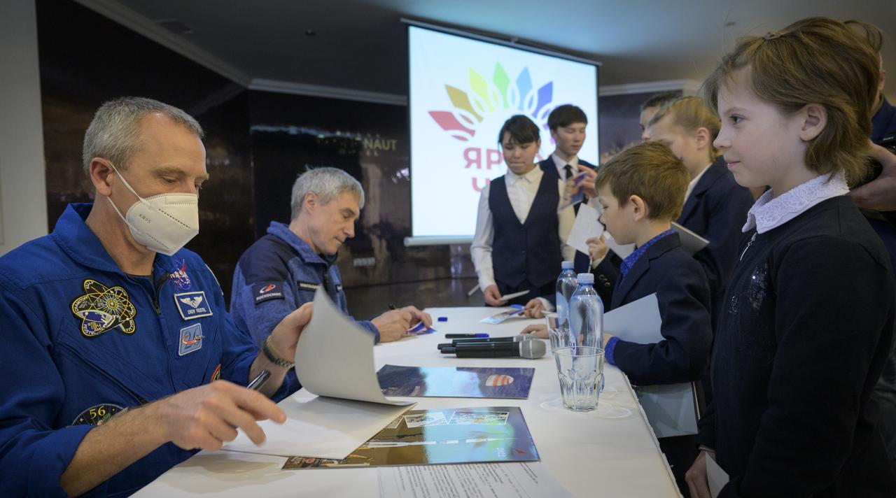 NASA Astronaut Office Representative, astronaut Drew Feustel, left, and Roscosmos Executive director of Human Spaceflight Programs Sergei Krikalev, give autographs to children from a local school, Monday, March 28, 2022, at the Cosmonaut Hotel in Karaganda, Kazakhstan. The two were part of an earlier meeting where NASA, Roscosmos, and Russian Search and Recovery Forces meet to discuss the readiness for the landing of Expedition 66 crew members Mark Vande Hei of NASA, and Pyotr Dubrov, and Anton Shkaplerov of Roscosmos. Vande Hei and Dubrov will be returning to Earth after logging 355 days in space as members of Expeditions 64-66 aboard the International Space Station. For Vande Hei, his mission is the longest single spaceflight by a U.S. astronaut in history. Shkaplerov will be returning after 176 days in space, serving as a Flight Engineer for Expedition 65 and commander of Expedition 66. Photo Credit: (NASA/Bill Ingalls)