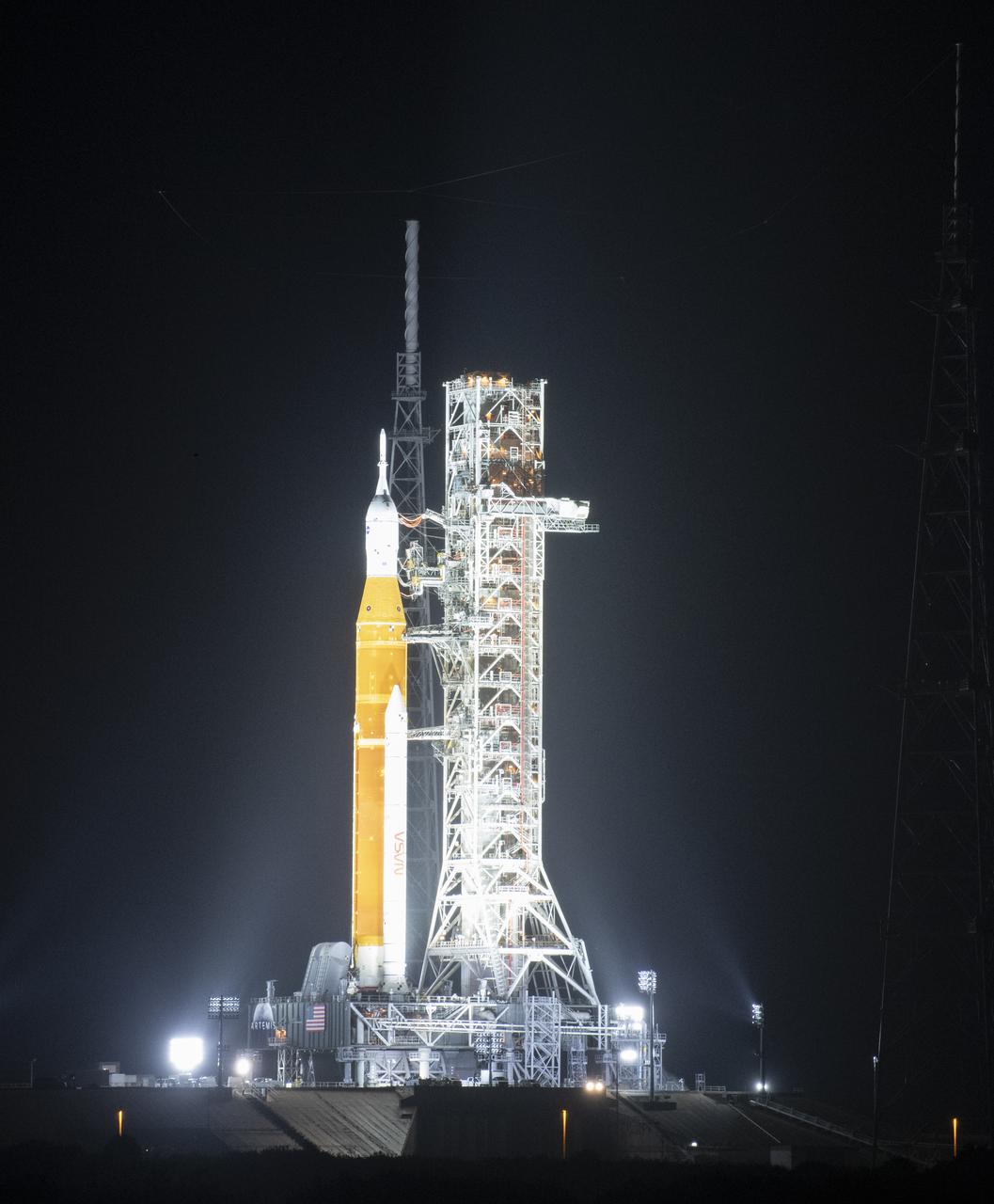 NASA’s Space Launch System (SLS) rocket with the Orion spacecraft aboard is seen atop a mobile launcher at Launch Complex 39B illuminated by spotlights, Saturday, April 2, 2022, as the Artemis I launch team conducts the wet dress rehearsal test at NASA’s Kennedy Space Center in Florida. Ahead of NASA’s Artemis I flight test, the wet dress rehearsal will run the Artemis I launch team through operations to load propellant, conduct a full launch countdown, demonstrate the ability to recycle the countdown clock, and drain the tanks to practice timelines and procedures for launch.  Photo Credit: (NASA/Joel Kowsky)