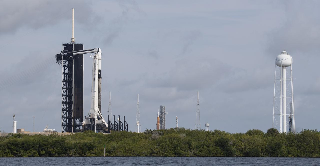 NASA’s Space Launch System (SLS) rocket with the Orion spacecraft aboard is seen atop a mobile launcher at Launch Complex 39B as the Artemis I launch team prepares for the next attempt of the wet dress rehearsal test, right, as a SpaceX Falcon 9 rocket with the company's Crew Dragon spacecraft aboard is seen on the launch pad at Launch Complex 39A as preparations continue for Axiom Mission 1 (Ax-1), Wednesday, April 6, 2022, at NASA’s Kennedy Space Center in Florida. The Ax-1 mission is the first private astronaut mission to the International Space Station.  Ax-1 crew members Commander Michael López-Alegría of Spain and the United States, Pilot Larry Connor of the United States, and Mission Specialists Eytan Stibbe of Israel, and Mark Pathy of Canada are scheduled to launch on April 8 from Launch Complex 39A at the Kennedy Space Center. Photo Credit: (NASA/Joel Kowsky)