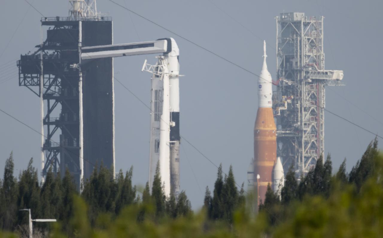 NASA’s Space Launch System (SLS) rocket with the Orion spacecraft aboard is seen atop a mobile launcher at Launch Complex 39B as the Artemis I launch team prepares for the next attempt of the wet dress rehearsal test, right, as a SpaceX Falcon 9 rocket with the company's Crew Dragon spacecraft aboard is seen on the launch pad at Launch Complex 39A as preparations continue for Axiom Mission 1 (Ax-1), Wednesday, April 6, 2022, at NASA’s Kennedy Space Center in Florida. The Ax-1 mission is the first private astronaut mission to the International Space Station.  Ax-1 crew members Commander Michael López-Alegría of Spain and the United States, Pilot Larry Connor of the United States, and Mission Specialists Eytan Stibbe of Israel, and Mark Pathy of Canada are scheduled to launch on April 8 from Launch Complex 39A at the Kennedy Space Center. Photo Credit: (NASA/Joel Kowsky)