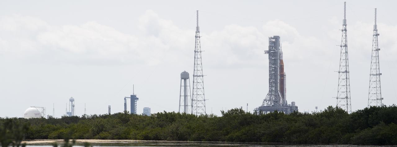 NASA’s Space Launch System (SLS) rocket with the Orion spacecraft aboard is seen atop a mobile launcher at Launch Complex 39B as the Artemis I launch team prepares for the next attempt of the wet dress rehearsal test, right, as a SpaceX Falcon 9 rocket with the company's Crew Dragon spacecraft aboard is seen on the launch pad at Launch Complex 39A as preparations continue for Axiom Mission 1 (Ax-1), Wednesday, April 6, 2022, at NASA’s Kennedy Space Center in Florida. The Ax-1 mission is the first private astronaut mission to the International Space Station.  Ax-1 crew members Commander Michael López-Alegría of Spain and the United States, Pilot Larry Connor of the United States, and Mission Specialists Eytan Stibbe of Israel, and Mark Pathy of Canada are scheduled to launch on April 8 from Launch Complex 39A at the Kennedy Space Center. Photo Credit: (NASA/Joel Kowsky)