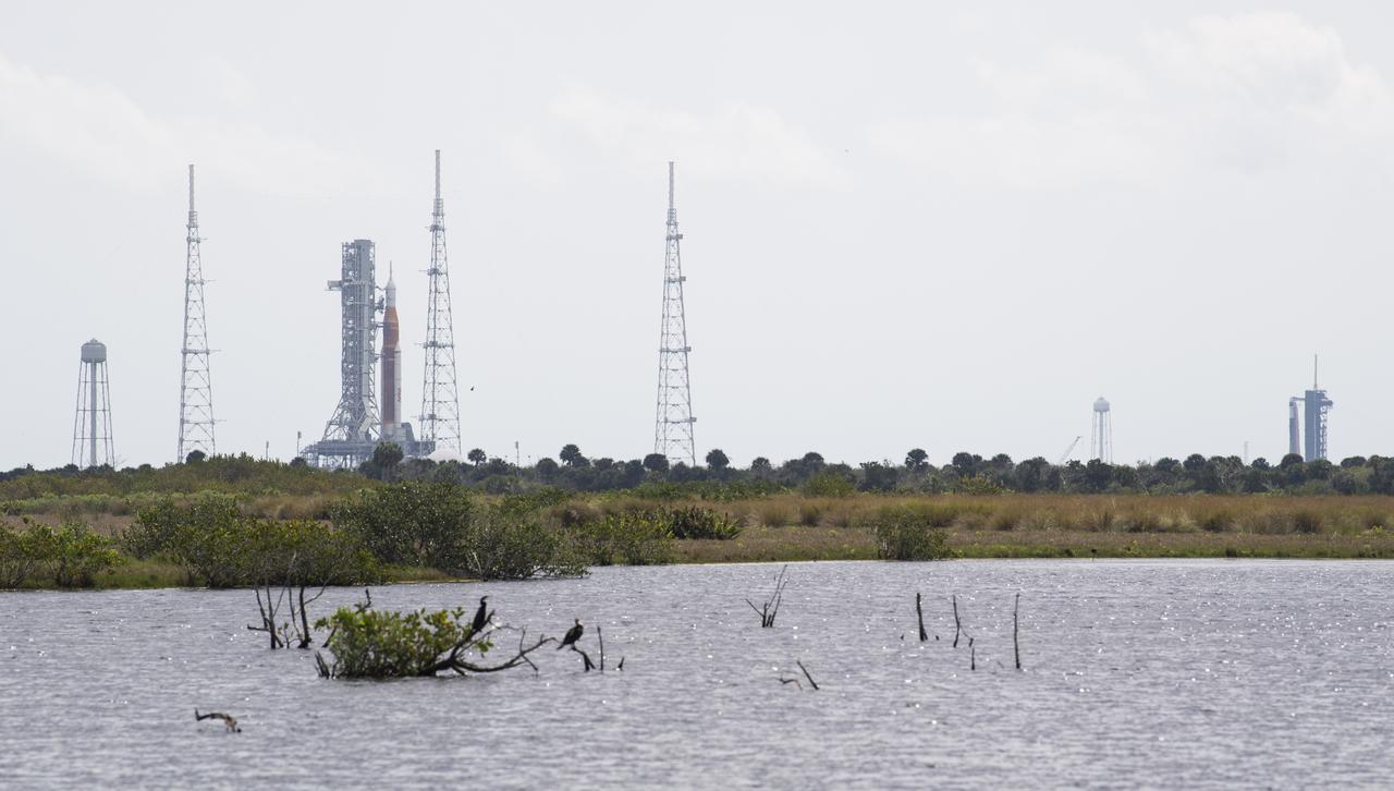 NASA’s Space Launch System (SLS) rocket with the Orion spacecraft aboard is seen atop a mobile launcher at Launch Complex 39B as the Artemis I launch team prepares for the next attempt of the wet dress rehearsal test, left, as a SpaceX Falcon 9 rocket with the company's Crew Dragon spacecraft aboard is seen on the launch pad at Launch Complex 39A as preparations continue for Axiom Mission 1 (Ax-1), Wednesday, April 6, 2022, at NASA’s Kennedy Space Center in Florida. The Ax-1 mission is the first private astronaut mission to the International Space Station.  Ax-1 crew members Commander Michael López-Alegría of Spain and the United States, Pilot Larry Connor of the United States, and Mission Specialists Eytan Stibbe of Israel, and Mark Pathy of Canada are scheduled to launch on April 8 from Launch Complex 39A at the Kennedy Space Center. Photo Credit: (NASA/Joel Kowsky)
