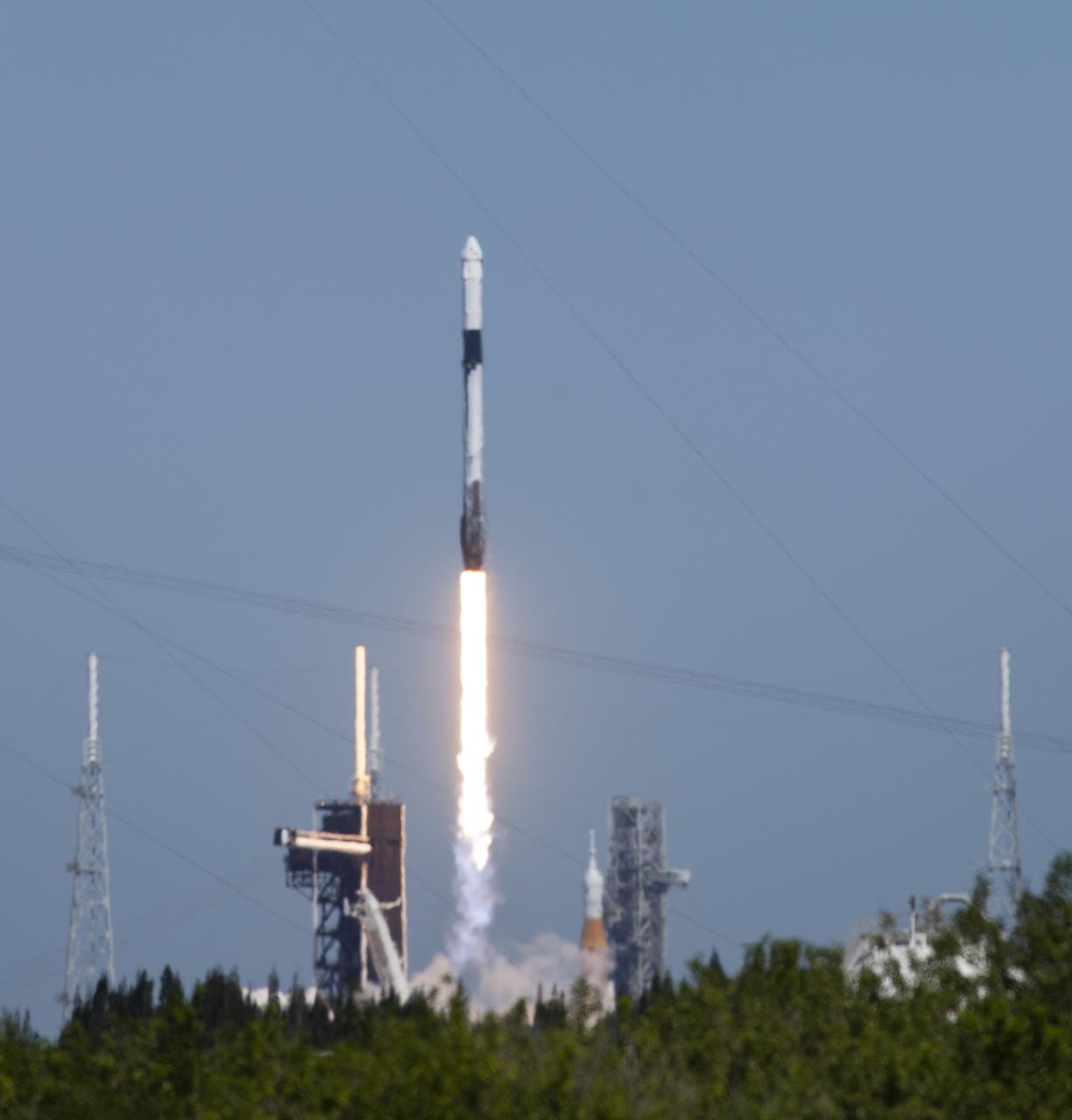 NASA’s Space Launch System (SLS) rocket with the Orion spacecraft aboard is seen atop a mobile launcher at Launch Complex 39B, right, as a SpaceX Falcon 9 rocket carrying the company's Crew Dragon spacecraft is launched on Axiom Mission 1 (Ax-1) to the International Space Station with Commander Michael López-Alegría of Spain and the United States, Pilot Larry Connor of the United States, and Mission Specialists Eytan Stibbe of Israel, and Mark Pathy of Canada aboard, Friday, April 8, 2022, at NASA’s Kennedy Space Center in Florida. The Ax-1 mission is the first private astronaut mission to the International Space Station. López-Alegría, Connor, Pathy, Stibbe launched at 11:17 a.m. from Launch Complex 39A at the Kennedy Space Center to begin their 10-day mission. Photo Credit: (NASA/Joel Kowsky)