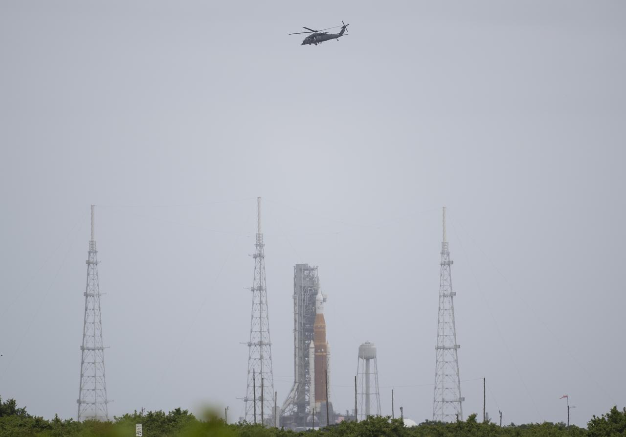 A helicopter is seen flying past NASA’s Space Launch System (SLS) rocket with the Orion spacecraft aboard atop a mobile launcher at Launch Complex 39B, Thursday, April 21, 2022, at NASA’s Kennedy Space Center in Florida. Photo Credit: (NASA/Joel Kowsky)