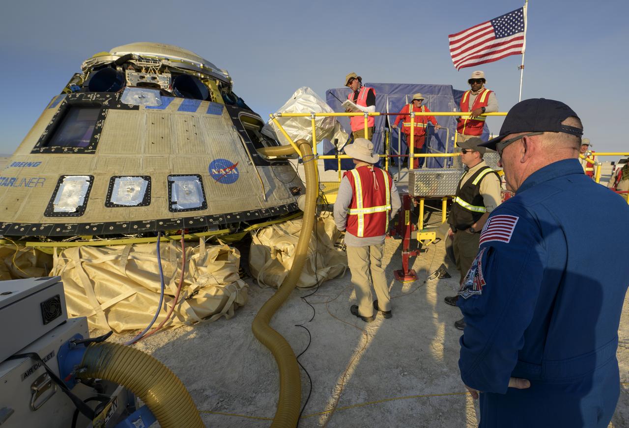 NASA astronaut Butch Wilmore, right, watches as teams work around Boeing’s CST-100 Starliner spacecraft after it landed at White Sands Missile Range’s Space Harbor, Wednesday, May 25, 2022, in New Mexico. Boeing’s Orbital Flight Test-2 (OFT-2) is Starliner’s second uncrewed flight test to the International Space Station as part of NASA's Commercial Crew Program. OFT-2 serves as an end-to-end test of the system's capabilities. Photo Credit: (NASA/Bill Ingalls)
