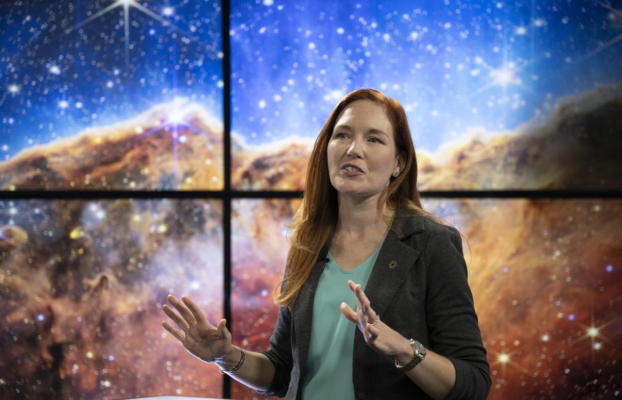 NASA James Webb Space Telescope Deputy Project Scientist for Communications Amber Straughn speaks about the infrared image of the star-forming region called NGC 3324 in the Carina Nebula as it is shown on a screen during a broadcast releasing the telescope’s first full-color images, Tuesday, July 12, 2022, at NASA’s Goddard Space Flight Center in Greenbelt, Md.  The first full-color images and spectroscopic data from the James Webb Space Telescope, a partnership with ESA (European Space Agency) and the Canadian Space Agency (CSA), are a demonstration of the power of Webb as the telescope begins its science mission to unfold the infrared universe. Photo Credit: (NASA/Bill Ingalls)