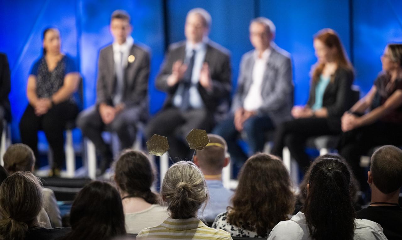 A NASA Social attendee is seen wearing a headband featuring Webb mirrors during a briefing with NASA Public Affairs Officer Alise Fisher, left, NASA James Webb Space Telescope Program Scientist and Astrophysics Division Chief Scientist Eric Smith, second from left, NASA James Webb Space Telescope Deputy Project Scientist for Exoplanet Science Knicole Colón, third from left, NASA James Webb Space Telescope Project Scientist at ESA (European Space Agency) Christopher Evans, fourth from left, NASA James Webb Space Telescope project scietntist, Space Telescope Science Institute, Klaus Pontoppidan, fourth from right, Principal Investigator for the Canadian Near-Infrared Imager and Slitless Spectrograph at the University of Montreal René Doyon, third from right, NASA James Webb Space Telescope Deputy Project Scientist for Communications Amber Straughn, second from right, and NASA James Webb Space Telescope Operations Project Scientist Jane Rigby, right, following the release of the first full-color images from NASA’s James Webb Space Telescope, Tuesday, July 12, 2022, at NASA’s Goddard Space Flight Center in Greenbelt, Md.  The first full-color images and spectroscopic data from the James Webb Space Telescope, a partnership with ESA (European Space Agency) and the Canadian Space Agency (CSA), are a demonstration of the power of Webb as the telescope begins its science mission to unfold the infrared universe. Photo Credit: (NASA/Bill Ingalls)