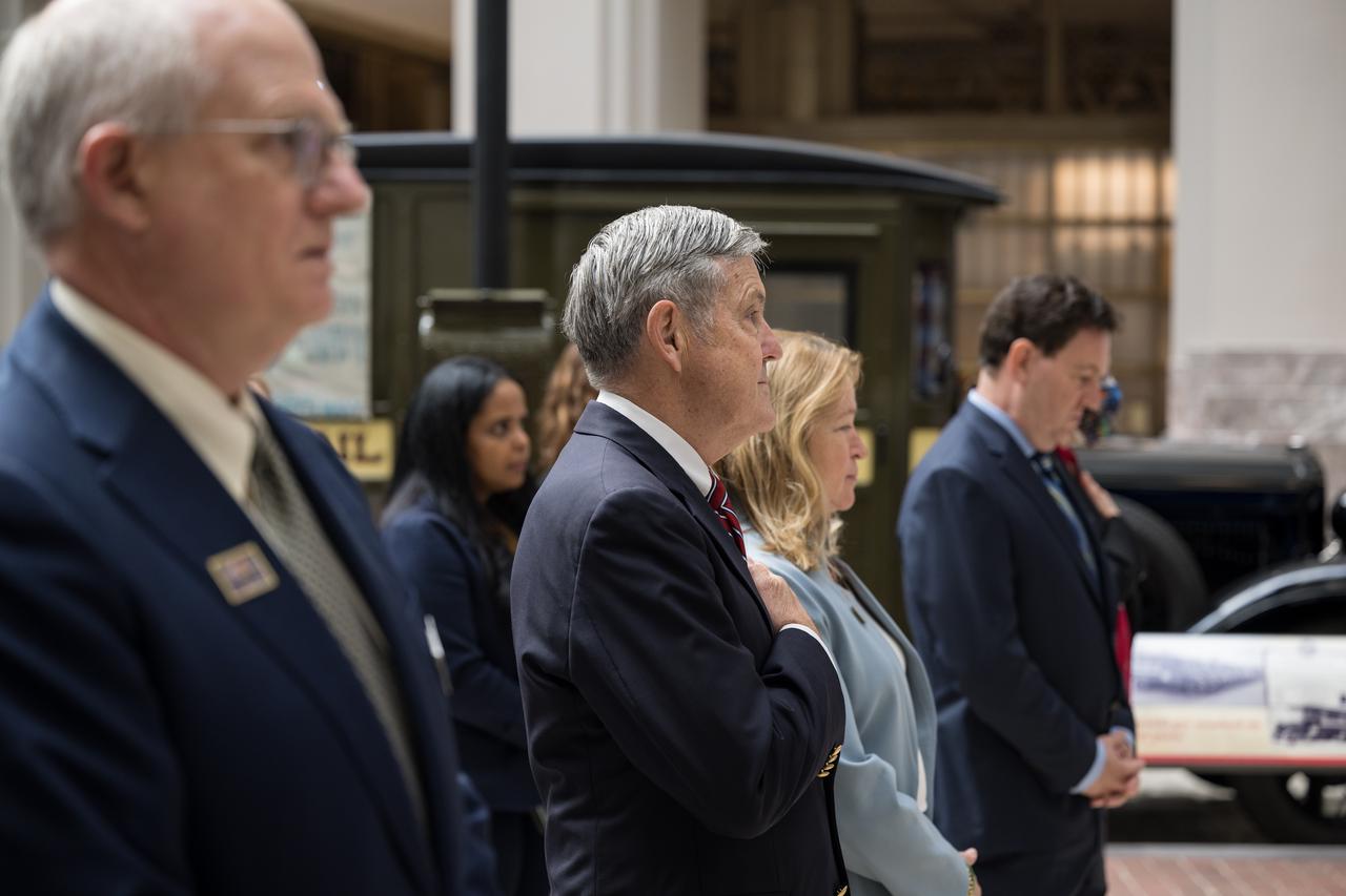 NASA Associate Administrator and former astronaut, Bob Cabana, second from left, and Smithsonian Institution Under Secretary for Service and Research, Ellen Stofan, third from left, are seen during the singing of the national anthem at the first-day-of-issue event for the United States Postal Service’s new stamp celebrating NASA’s James Webb Space Telescope (JWST) on Thursday, Sept. 8, 2022, at the Smithsonian’s National Postal Museum in Washington. The stamp, which features an illustration of the observatory, honors Webb’s mission to explore the unknown in our universe – solving mysteries in our solar system, looking beyond to distant worlds around other stars, and probing the structures and origins of our universe and our place in it. Photo Credit: (NASA/Aubrey Gemignani)