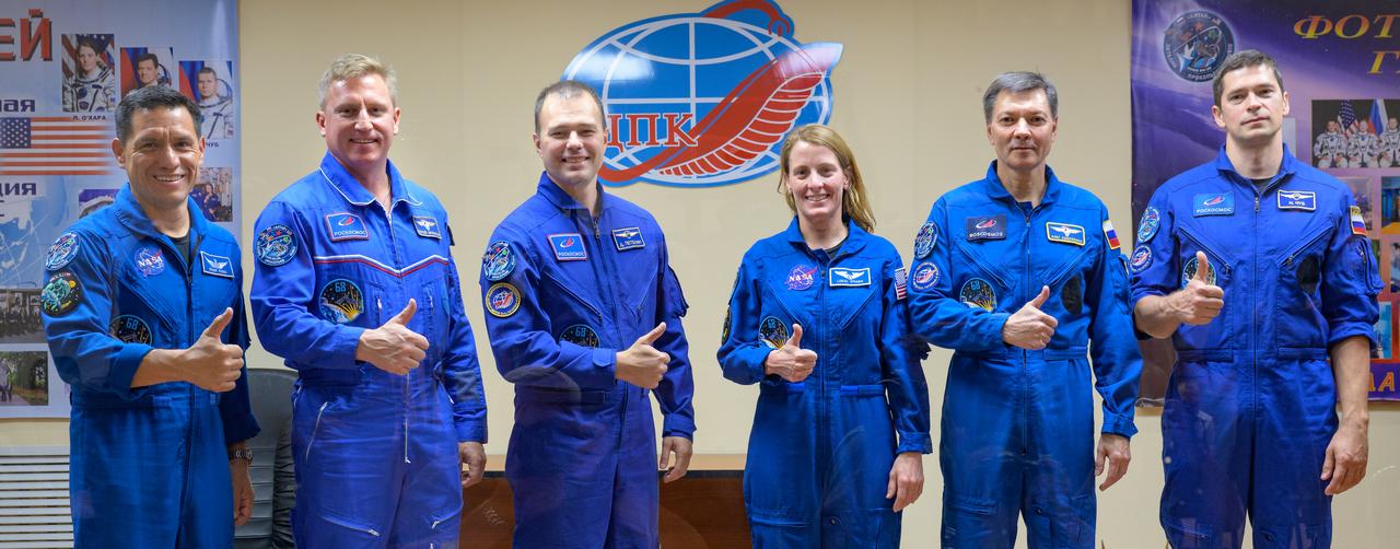 Expedition 68 astronaut Frank Rubio of NASA, left, cosmonauts Sergey Prokopyev and Dmitri Petelin of Roscosmos, along with Expedition 68 backup crewmembers Loral O'Hara of NASA, Oleg Kononenko and Nikolai Chub of Roscosmos, right, are seen in quarantine, behind glass, at the conclusion of a press conference, Tuesday, Sept. 20, 2022, at the Cosmonaut Hotel in Baikonur, Kazakhstan. Rubio, Prokopyev, and Petelin are scheduled to launch to the International Space Station aboard the Soyuz MS-22 spacecraft on Sept. 21. Photo Credit: (NASA/Bill Ingalls)