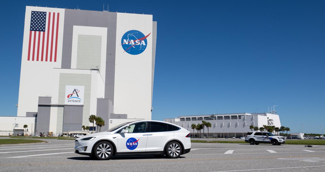 A vehicle carrying two members of NASA’s SpaceX Crew 5 mission passes by the Vehicle Assembly Building as it returns to the Neil A. Armstrong Operations and Checkout Building from Launch Complex 39A following the completion of a dress rehearsal for the Crew 5 launch, Sunday, Oct. 2, 2022, at NASA’s Kennedy Space Center in Florida. NASA’s SpaceX Crew-5 mission is the fifth crew rotation mission of the SpaceX Crew Dragon spacecraft and Falcon 9 rocket to the International Space Station as part of the agency’s Commercial Crew Program. NASA astronauts Nicole Mann and Josh Cassada, Japan Aerospace Exploration Agency (JAXA) astronaut Koichi Wakata, and Roscosmos cosmonaut Anna Kikina are scheduled to launch at 12:00 p.m. EDT on Oct. 5, from Launch Complex 39A at the Kennedy Space Center. Photo Credit: (NASA/Joel Kowsky)