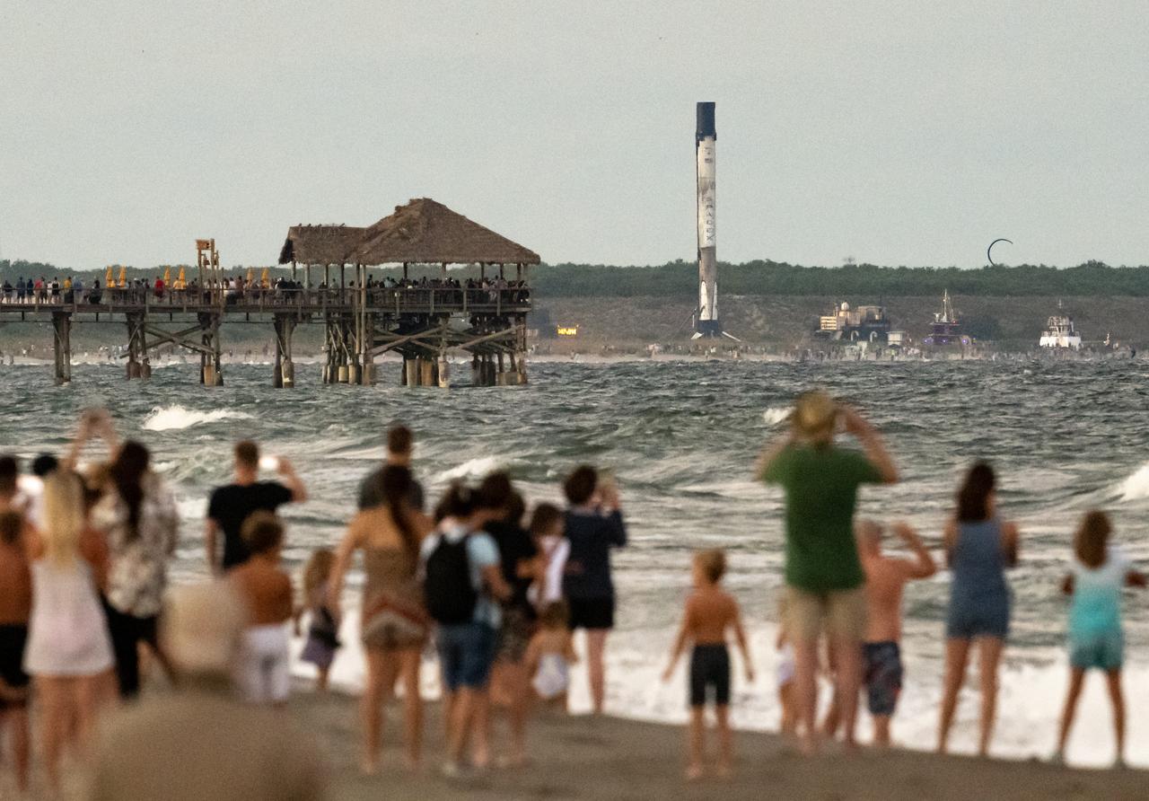 Beach goers watch as the Falcon 9 rocket booster used for NASA’s SpaceX Crew-5 launch, sitting atop the autonomous spaceport drone ship (ASDS), is towed into Port Canaveral, Saturday, Oct. 8, 2022, in Cape Canaveral, Florida. NASA’s SpaceX Crew-5 mission is the fifth crew rotation mission of the SpaceX Crew Dragon spacecraft and Falcon 9 rocket to the International Space Station as part of the agency’s Commercial Crew Program. NASA astronauts Nicole Mann and Josh Cassada, Japan Aerospace Exploration Agency (JAXA) astronaut Koichi Wakata, and Roscosmos cosmonaut Anna Kikina launched on Oct. 5 from Launch Complex 39A at the Kennedy Space Center.  Photo Credit: (NASA/Bill Ingalls)