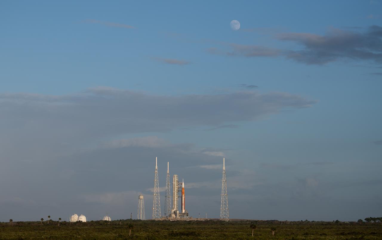 The Moon is seen as it rises above NASA’s Space Launch System (SLS) rocket with the Orion spacecraft aboard is seen atop a mobile launcher at Launch Pad 39B as preparations for launch continue, Saturday, Nov. 5, 2022, at NASA’s Kennedy Space Center in Florida. NASA’s Artemis I flight test is the first integrated test of the agency’s deep space exploration systems: the Orion spacecraft, SLS rocket, and supporting ground systems. Launch of the uncrewed flight test is targeted for Nov. 14 at 12:07 a.m. EST. Photo Credit: (NASA/Joel Kowsky)