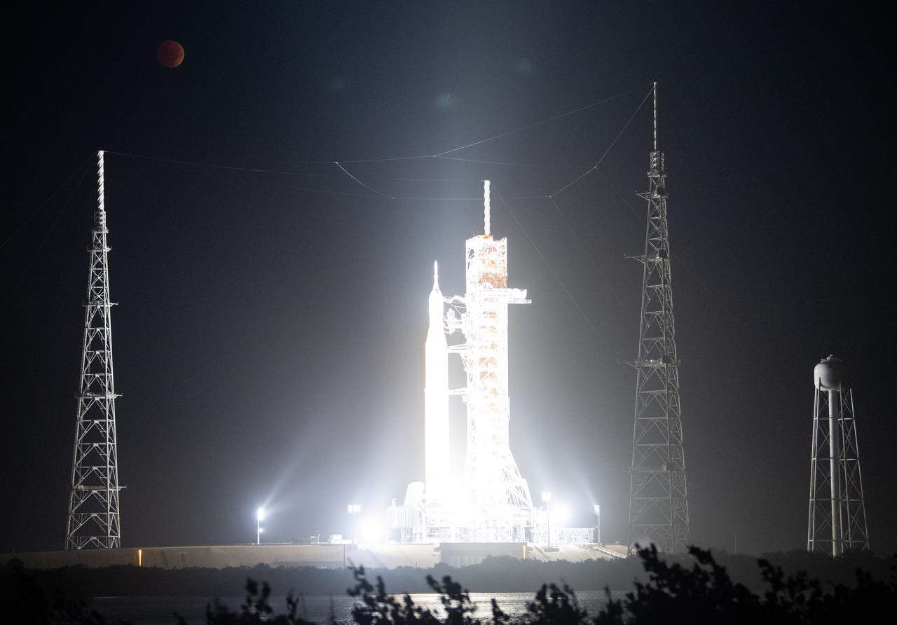 The Moon is seen during a total lunar eclipse above NASA’s Space Launch System (SLS) rocket with the Orion spacecraft aboard atop a mobile launcher at Launch Pad 39B, Tuesday, Nov. 8, 2022, at NASA’s Kennedy Space Center in Florida. NASA’s Artemis I flight test is the first integrated test of the agency’s deep space exploration systems: the Orion spacecraft, SLS rocket, and supporting ground systems. Photo Credit: (NASA/Joel Kowsky)