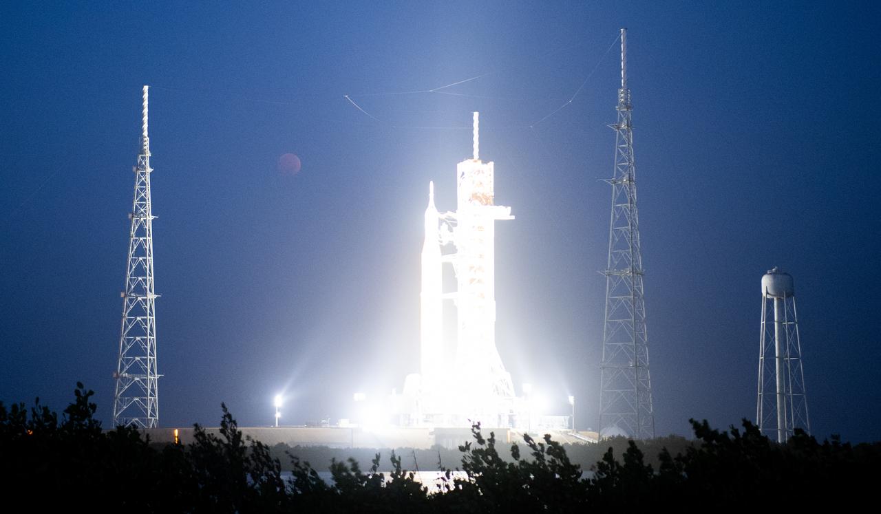 The Moon is seen during a total lunar eclipse above NASA’s Space Launch System (SLS) rocket with the Orion spacecraft aboard atop a mobile launcher at Launch Pad 39B, Tuesday, Nov. 8, 2022, at NASA’s Kennedy Space Center in Florida. NASA’s Artemis I flight test is the first integrated test of the agency’s deep space exploration systems: the Orion spacecraft, SLS rocket, and supporting ground systems. Photo Credit: (NASA/Joel Kowsky)