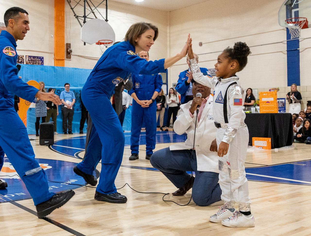 NASA astronaut Kayla Barron high fives a student during a visit to Amidon-Bowen Elementary School with fellow Expedition 66 crewmates NASA astronauts Raja Chari, Tom Marshburn, and Mark Vande Hei, and NASA Administrator Bill Nelson, Thursday, Dec. 8, 2022, in Washington. Vande Hei spent 355 days in space as a member of Expedition 65/66 and was joined during Expedition 66 by Marshburn, Chari, and Barron who spent 177 days onboard the International Space Station. Photo Credit: (NASA/Keegan Barber)