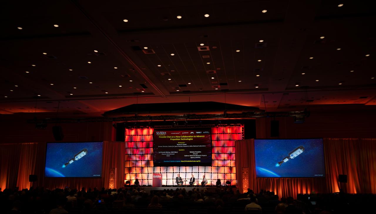 An artists concept of the Demonstration Rocket for Agile Cislunar Operations, or DRACO, spacecraft is seen on a screen as Steve Howe, former director of the Center for Space Nuclear Research at the Idaho National Laboratory, left, NASA Deputy Administrator Pam Melroy, center, and Stefanie Tompkins, director of the Defense Advance Research Projects Agency (DARPA), right, participate in a fireside chat announcing a new collaboration on nuclear thermal propulsion at the American Institute of Aeronautics and Astronautics SciTech Forum, Tuesday, Jan. 24, 2023, at the Gaylord National Resort and Convention Center in National Harbor, Md. NASA and the Defense Advanced Research Projects Agency (DARPA) will partner on the Demonstration Rocket for Agile Cislunar Operations, or DRACO, project to develop and demonstrate in-space a nuclear thermal engine. Photo Credit: (NASA/Joel Kowsky)