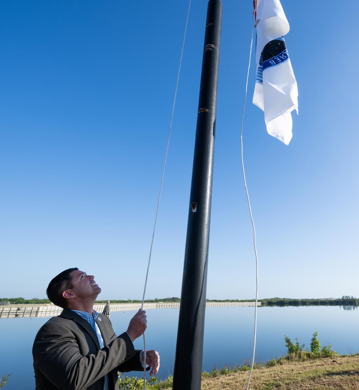 Trip Healey, manager, Program Control & Integration for NASA’s Commercial Crew Program, raises the SpaceX Crew-6 flag, Wednesday, Feb. 22, 2023, at NASA’s Kennedy Space Center in Florida. NASA’s SpaceX Crew-6 mission is the sixth crew rotation mission of the SpaceX Dragon spacecraft and Falcon 9 rocket to the International Space Station as part of the agency’s Commercial Crew Program. NASA astronauts Stephen Bowen and Warren "Woody" Hoburg, UAE (United Arab Emirates) astronaut Sultan Alneyadi, and Roscosmos cosmonaut Andrey Fedyaev are scheduled to launch at 1:45 a.m. EST on Feb. 27 from Launch Complex 39A at the Kennedy Space Center. Photo Credit: (NASA/Joel Kowsky)