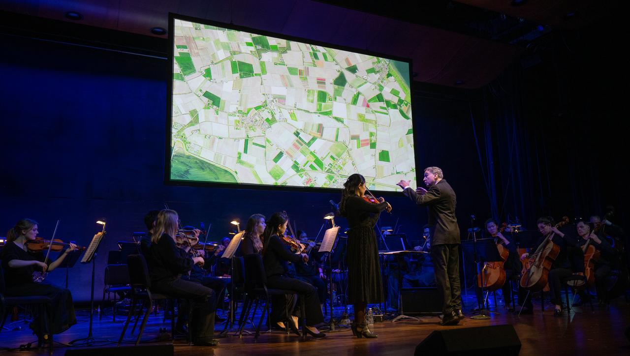 Emil de Cou conducts the Catholic University Orchestra, Wednesday, April 5, 2023, during the “Our Blue Planet” concert at the John F. Kennedy Center for the Performing Arts in Washington. Jeannie Schulz, widow of Peanuts gang creator Charles M. Schulz, was awarded a NASA Exceptional Achievement Medal by NASA Administrator Bill Nelson at the concert. Snoopy rode along as the zero gravity indicator on NASA’s Artemis I mission as part of a partnership with the agency and continues to help NASA inspire kids of all ages to follow along with Artemis missions.  Photo Credit: (NASA/Joel Kowsky)