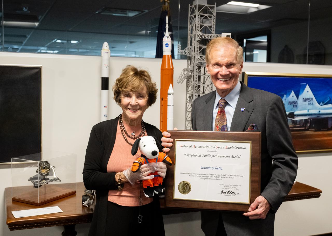 NASA Administrator Bill Nelson, right, and Jeannie Schulz, widow of Peanuts gang creator Charles M. Schulz, holding the Artemis I Snoopy zero gravity indicator, left, pose for a picture with the NASA Exceptional Achievement Medal plaque, Wednesday, April 5, 2023, at the Mary W. Jackson NASA Headquarters building in Washington. Schulz was awarded a NASA Exceptional Achievement Medal by Administrator Nelson at an “Our Blue Planet” concert at the John F. Kennedy Center for the Performing Arts. Snoopy rode along as the zero gravity indicator on NASA’s Artemis I mission as part of a partnership with the agency and continues to help NASA inspire kids of all ages to follow along with Artemis missions. As part of the visit, Schulz showed the flown Artemis I Snoopy zero gravity indicator before it goes to its final home for display at the Schulz Museum in Santa Rosa, California.  Photo Credit: (NASA/Joel Kowsky)