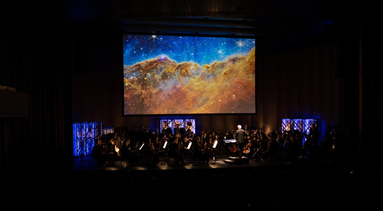 Maestro Piotr Gajewski conducts the National Philharmonic  in the world premier performance of Henry Dehlinger’s “Cosmic Cycles,” Thursday, May 11, 2023, at Capital One Hall in Tysons, Va. “Cosmic Cycles: A Space Symphony” is a collaboration between composer Henry Dehlinger, NASA’s Goddard Space Flight Center, and the National Philharmonic that features a fusion of music and video in seven multimedia works on the Sun, Earth, Moon, Planets, and Cosmos.  Photo Credit: (NASA/Joel Kowsky)